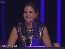 a woman is laughing in front of a microphone with the hashtag lialmeida05 on the bottom