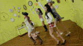 a group of girls are dancing in front of a wall of clocks