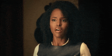 a woman with curly hair is wearing a pearl necklace and a leather dress