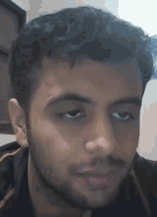 a man with a beard looks at the camera with a serious look on his face