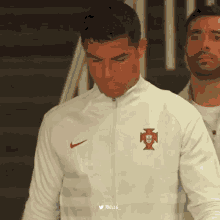 a man wearing a white nike jacket with a red cross on it
