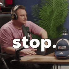 a man wearing headphones sits in front of a microphone with the word stop written on the screen