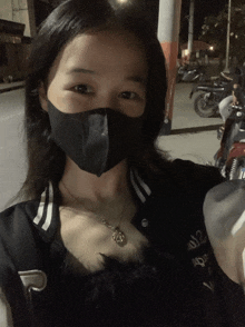 a woman wearing a black mask and a black jacket with the number 12 on the front