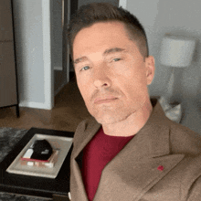 a man in a suit and red shirt is sitting in front of a coffee table