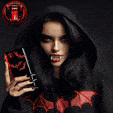 a woman in a black hoodie holds a cup of coffee and a cell phone