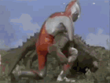 a man in a red and white suit is fighting a monster in a field .