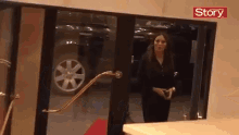 a woman is standing in front of a glass door with the word story written on it