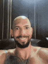 a shirtless bald man with a beard is smiling