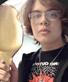 a young man wearing glasses and a shirt that says rio tuo on it is holding a banana