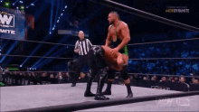 two men are wrestling in a wrestling ring with a referee in the background