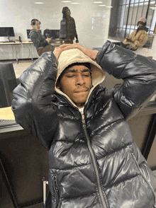 a man wearing a black jacket with a hood is laying down with his eyes closed
