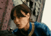 a close up of a woman 's face wearing a blue jacket with the letter t on it