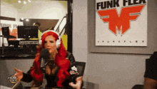 a woman with red hair is talking into a microphone in front of a sign for funk flex