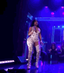 a woman in thigh high boots is standing on a stage in front of a microphone