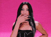 a woman with long curly hair is wearing a fur necklace and making a funny face on a pink background .