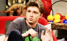 a young man is sitting on a couch in front of a basket of toys .