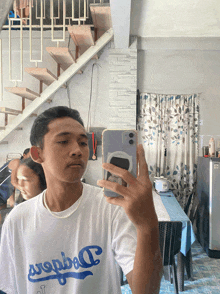 a young man taking a picture of himself with his phone in a room