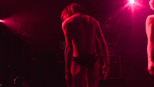a man without a shirt is holding a black guitar