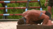 a man is doing push ups on a wooden block while a woman watches .