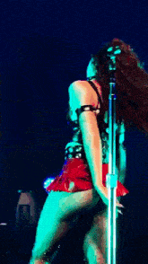 a woman in a red skirt is dancing on stage in front of a microphone