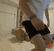 a man in a white shirt and black shorts is standing next to a cardboard box that says panasonic