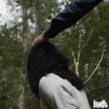 a person is holding another person 's hand in the woods and the word kosh is on the bottom