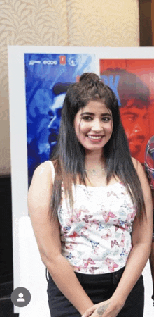 a woman is smiling in front of a poster that says ' a ' on it