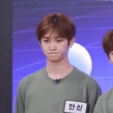 a young man wearing a green shirt is making a funny face .