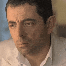 a close up of a man 's face with a white shirt and white jacket