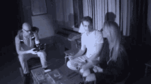 a group of people are sitting in a dark room and one of them is wearing glasses