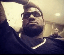 a man with a beard is taking a selfie with his hand on his head .