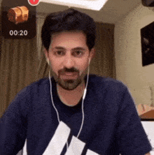 a man with a beard wearing headphones and a blue shirt