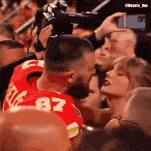 a man in a red jersey with the number 87 is kissing a woman in the crowd .