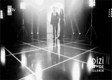 a black and white photo of a man and a woman walking down a stage .