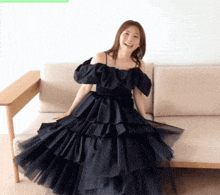 a woman in a long black dress is sitting on a couch