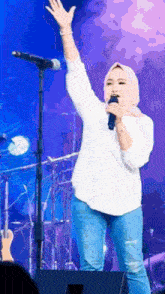 a woman singing into a microphone with her arm in the air