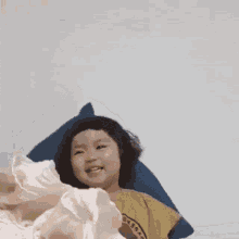 a little girl is laying on a bed with a pillow and a blanket .