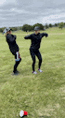 a couple of people are dancing in a field with a red cup in the foreground .