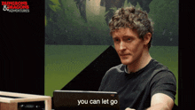 a man sitting in front of a laptop with the words you can let go on the screen