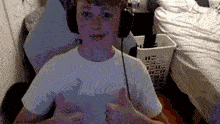 a young boy wearing headphones is giving a thumbs up sign