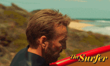 a man standing next to a surfboard with the word the surfer on it