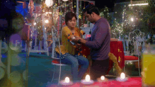 a man and a woman are sitting at a table with candles in front of them