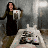 a woman holding a picture of a man standing next to a pioneer dj turntable