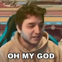 a man in a hoodie is sitting in a chair with his eyes closed and says oh my god .