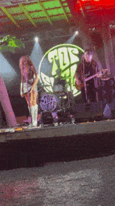 a man playing a guitar and a woman singing in front of a sign that says the