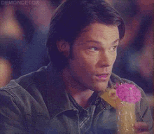 a man is drinking from a glass with a pink flower on it