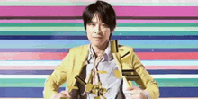 a man in a yellow jacket is standing in front of a colorful striped background .