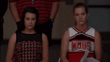 two cheerleaders are sitting next to each other and one has wmhs on her shirt