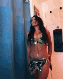 a woman in a bikini stands in front of a blue shower curtain