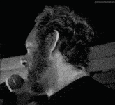 a black and white photo of a man with a beard and earring .